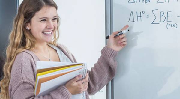 Student pointing toward math equation on white board